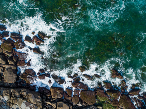 Overhead close up coastal view of ocean waves crashing onto rocky coast on the Australian shore - Australian Stock Image