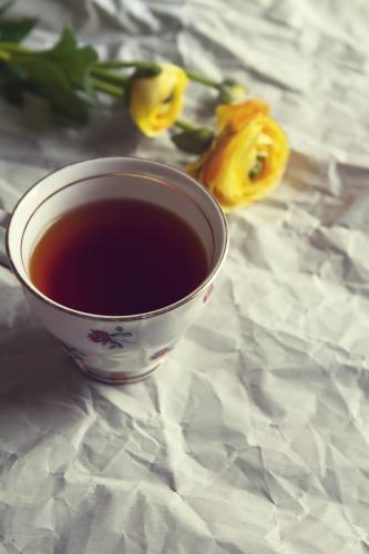 Overhead of cup of tea in vintage cup with yellow roses on crumpled paper background - Australian Stock Image