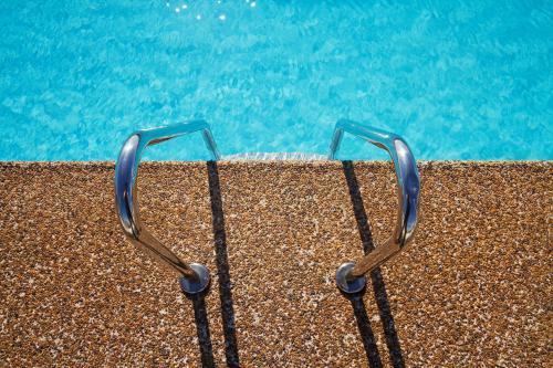 Overhead of pebble mix swimming pool edge with ladder forming graphic elements - Australian Stock Image