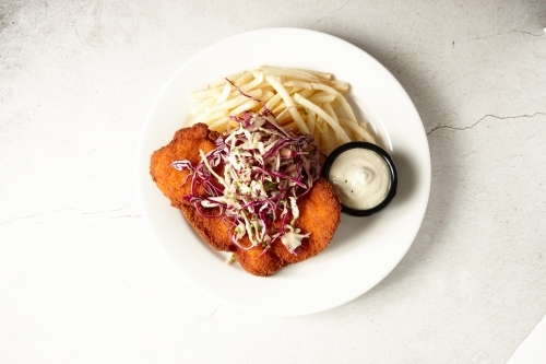 Overhead shot of chicken schnitzel with salad and fries on plate - Australian Stock Image