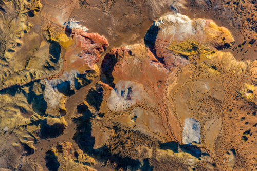 Overhead shot of white erosion patterns and green shrubs on orange desert soil - Australian Stock Image