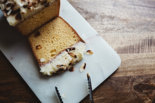 Overhead view of a sliced piece of almond cake on marble platter - Australian Stock Image
