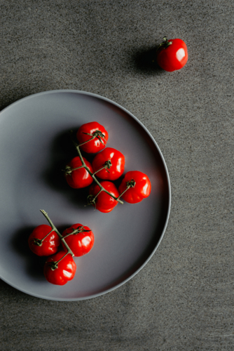 Overhead view of fresh, ripe homegrown vine picked organic heirloom red tomatoes on a plate - Australian Stock Image