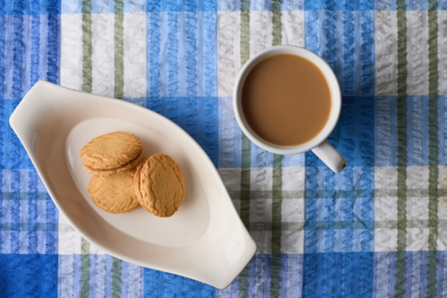 overhead view of Monte Carlo biscuits with coffee cup on blue tablecloth - Australian Stock Image