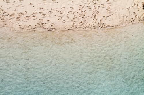 Overhead view of sandy beach waters edge with aqua blue water - Australian Stock Image