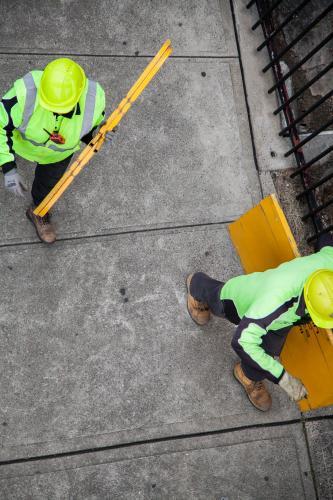 Overhead view of two workers in yellow carrying road signs