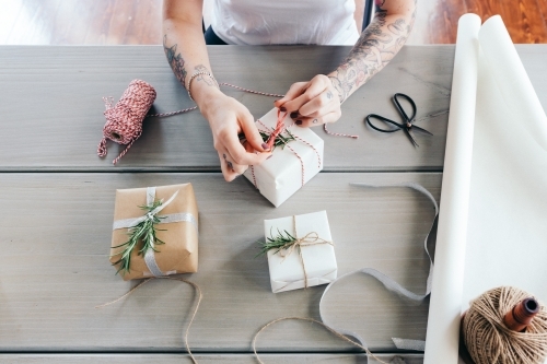 Overhead view of young girl wrapping Christmas presents in natural papers and twine - Australian Stock Image
