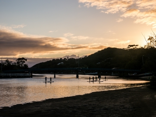 Paddle boarders on Currumbin Creek at sunrise - Australian Stock Image