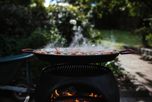 Paella cooks on an outdoor fire