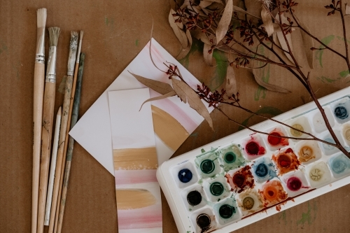 Paint brushes and paints with brush strokes on paper. - Australian Stock Image