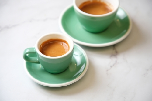 Pair of espressos in teal cup on marble table - Australian Stock Image