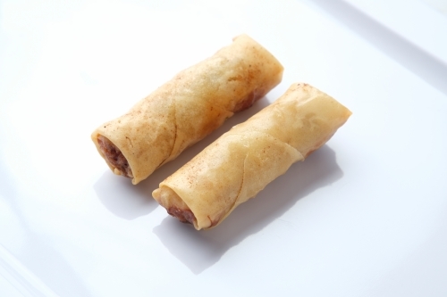 Pair of spring rolls on blank white plate - Australian Stock Image