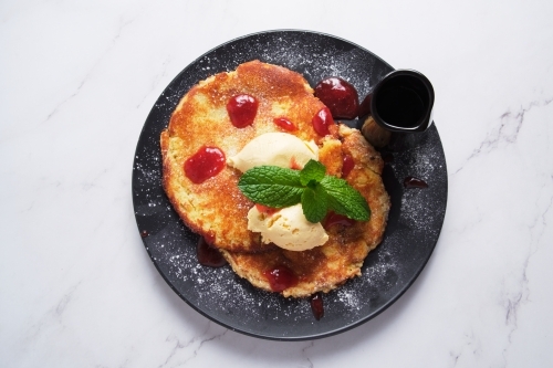 Pancakes served in a black plate topped with butter and mint - Australian Stock Image
