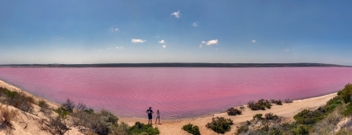 Pano of couple standing on shore of Hutt Lagoon / Pink Lake created by carotenoid-producing algae