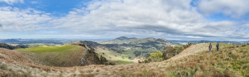 Panorama of hills and two people hiking together - Australian Stock Image