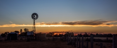 Panoramic view of countryside with a windmill silhouette - Australian Stock Image