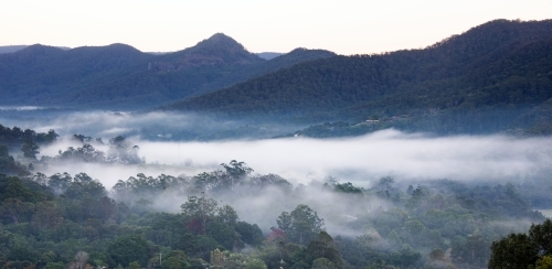 Panoramic view of misty valleys with mountains in the background. - Australian Stock Image