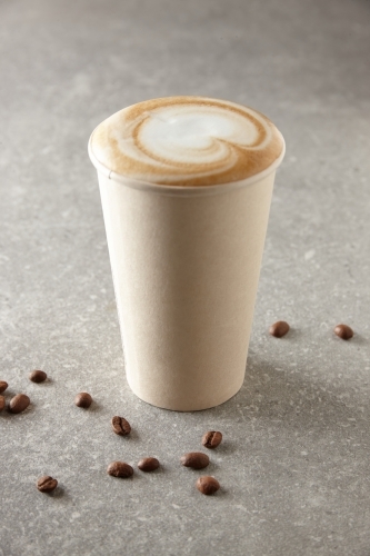 Paper coffee cup and coffee beans on table - Australian Stock Image