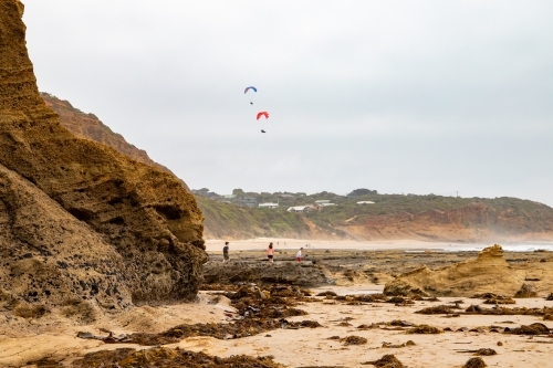 paragliders over beach at low tide
