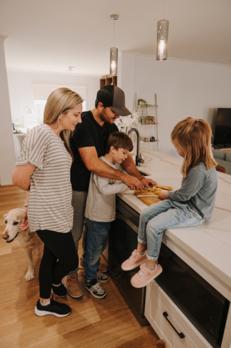 Parents teaching kids how to cut fruit in the kitchen - Australian Stock Image