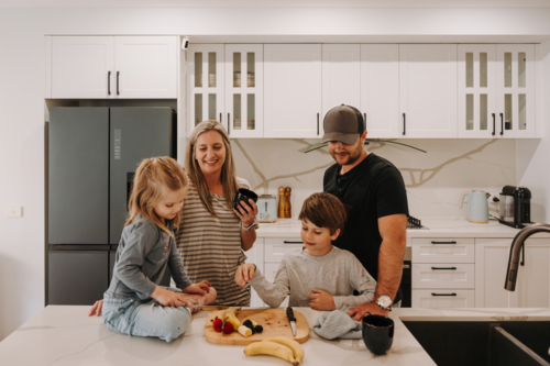 Parents teaching kids how to cut fruits in the kitchen. - Australian Stock Image