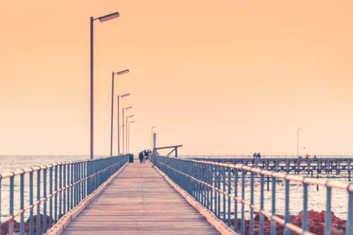 Partially defocused view of Moonta Bay jetty with people at dusk, Yorke Peninsula, South Australia - Australian Stock Image