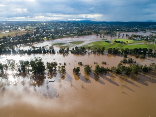 Patch of farmland paddock cut off by floodwater aerial view over flood and river - Australian Stock Image