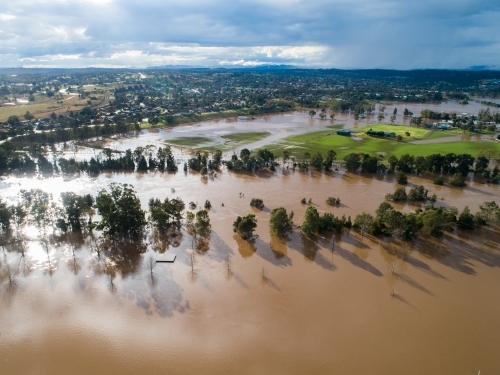 Patch of farmland paddock cut off by floodwater aerial view over flood and river