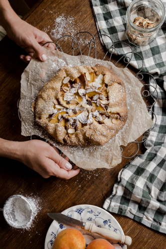 peach tart with hands on a timber tabletop - Australian Stock Image