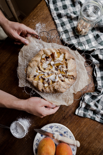 peach tart with hands on a timber tabletop - Australian Stock Image