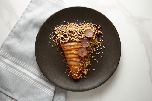 Peanut butter jam crepe topped with nuts and chocolate served in a black plate. - Australian Stock Image