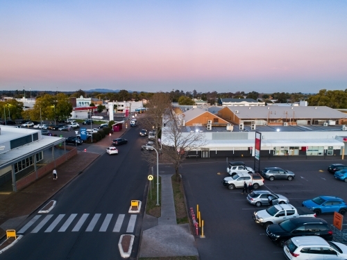 Pedestrian crossing between carpark and shopping centre in town at dusk seen from aerial view