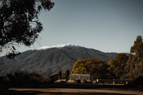 People at a looking at a snow-dusted Mt Bogong at the start of winter.