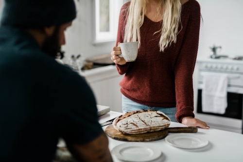 People at kitchen bench having a cup of coffee - Australian Stock Image