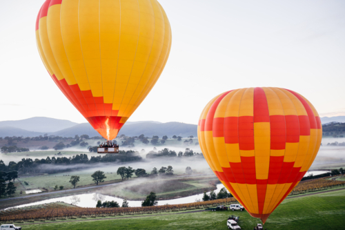 people Hot Air Ballooning in two orange and yellow balloons on cold morning - Australian Stock Image