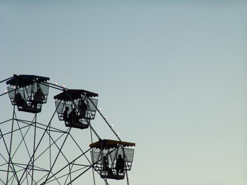 People in a ferris wheel silhouetted against a blue sky