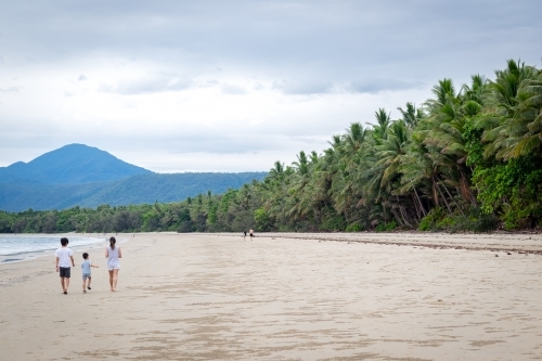 people leisurely walking along a tropical beachscape - Australian Stock Image