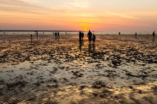 People silhouetted in the colourful sunset at Menindee Beach - Australian Stock Image
