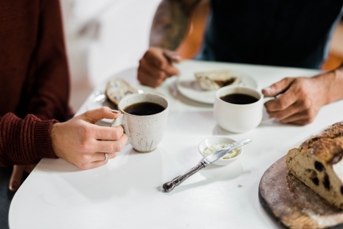 People sitting at a table drinking coffee and eating artisan bread - Australian Stock Image