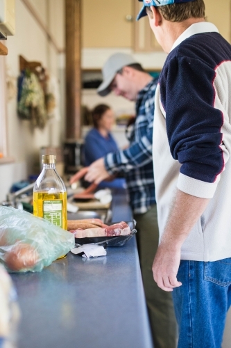 People standing near a kitchen sink helping to prepare food for lunch - Australian Stock Image
