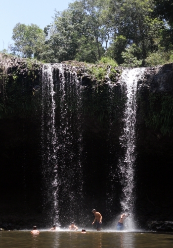 People swimming at the base of a waterfall - Australian Stock Image