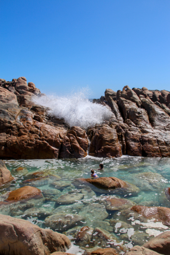 People swimming in natural ocean spa amongst rocks - Australian Stock Image