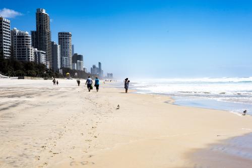 People walking along Gold Coast beach in summer with city in background