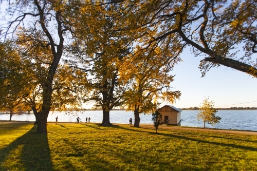 People walking around a lake at sunset in Autumn - Australian Stock Image