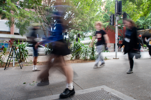 People walking on city footpath with motion blur in urban street environment - Australian Stock Image