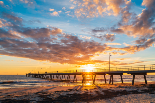 People walking on Glenelg Beach jetty during beautiful sunset, South Australia - Australian Stock Image