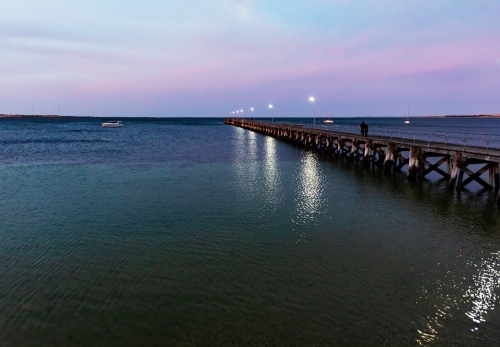 people walking on jetty in evening light - Australian Stock Image