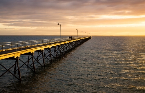 people walking on jetty in late afternoon light - Australian Stock Image