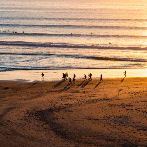 People walking on the beach at sunset in the summer - Australian Stock Image