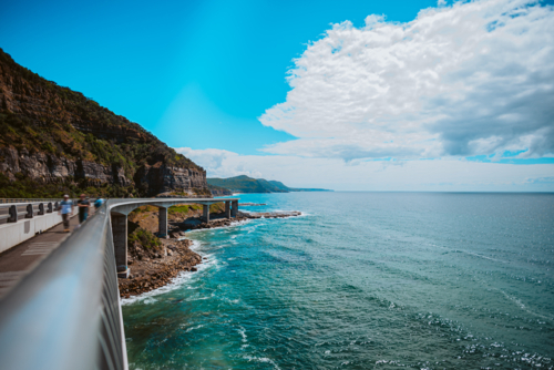 people walking on the sea cliff bridge overlooking the ocean - Australian Stock Image